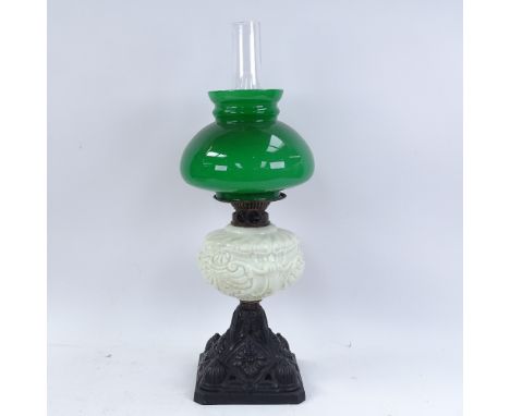 A painted cast-iron oil lamp, with milk glass font, green shade and chimney, overall height 56cm 