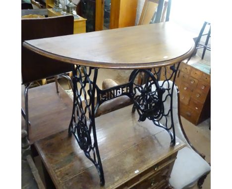 A mahogany demilune console table on a Singer sewing machine treadle base, W100cm, D47cm, H74cm 