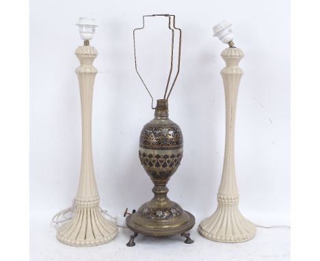 A Middle Eastern brass and black enamel table lamp, and a pair of cream painted wood table lamps, brass lamp height excluding