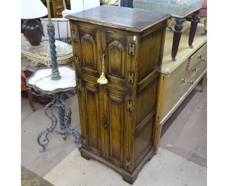 A Titchmarsh &amp; Goodwin Ipswich oak design music cabinet, with 4 fielded panelled cupboards doors, H-shaped brass hinges, 