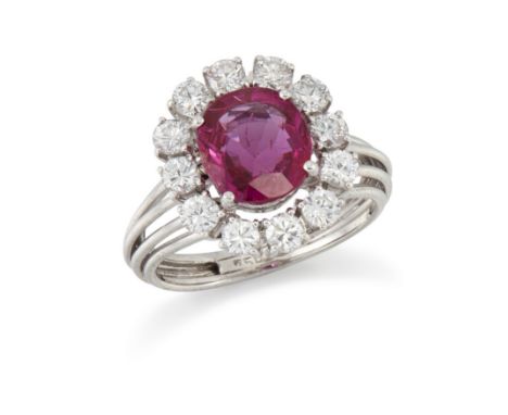 A ruby and diamond ring, the central oval mixed cut ruby in claw set mount within brilliant cut diamond surround, to openwork