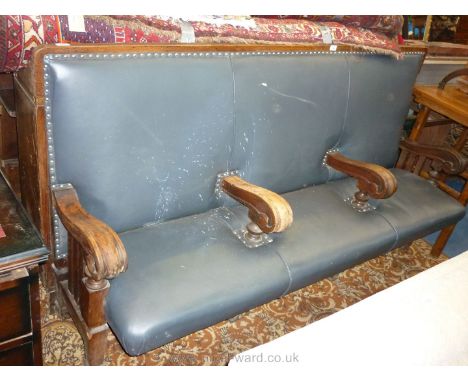 A very substantial Oak framed three seater Settle, upholstered in navy blue leatherette, having elegant integral arms/seat di