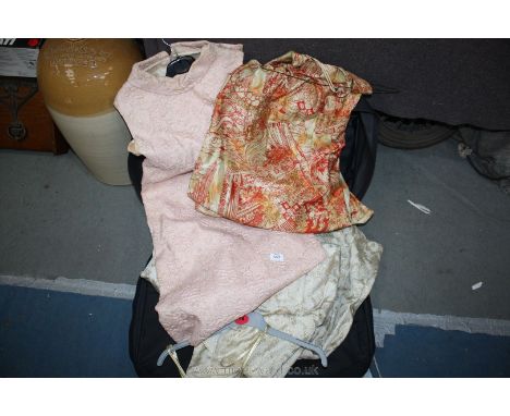 A suitcase with three vintage dresses.