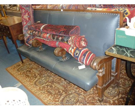 A very substantial Oak framed three seater Settle, upholstered in navy blue leatherette, having elegant integral arms/seat di