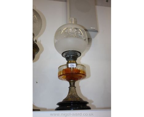 An Oil lamp with a glass reservoir and chimney, etched shaded glass with metal stem and black ceramic base.