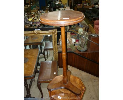 A Walnut and Mahogany Lamp Table/Plant Stand having a turned pillar and platform base raised on three spherical feet, 13'' di