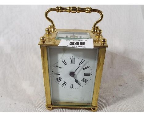 An early 20th century timepiece carriage clock, the brass and bevelled glass case raised on bun feet and surmounted by a bras