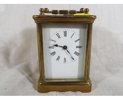 A brass cased carriage clock of traditional form, Roman numerals on a white dial with mechanical movement