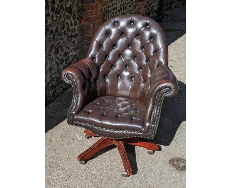 A reproduction brown leather 'Chesterfield' button back swivel armchair on fire legs and raised on castersLocation: 