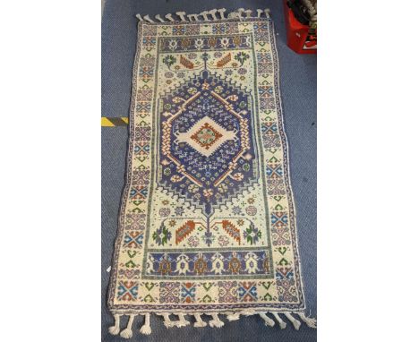 A handwoven Turkish Kazak design rug with a central symmetrical gull with repeating motifs around the border on a light green