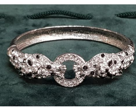 Black and white paste set panther bangle in green jewellery pouch.