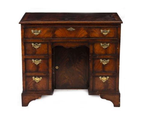 An 18th century style mahogany kneehole desk with one long and six short drawers around a recess with a cupboard door and rai