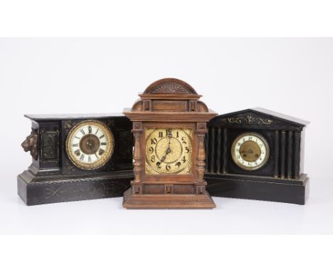 An American black mantle clock with lion mask ornament to either end; an old slate mantle clock with French movement and a Co