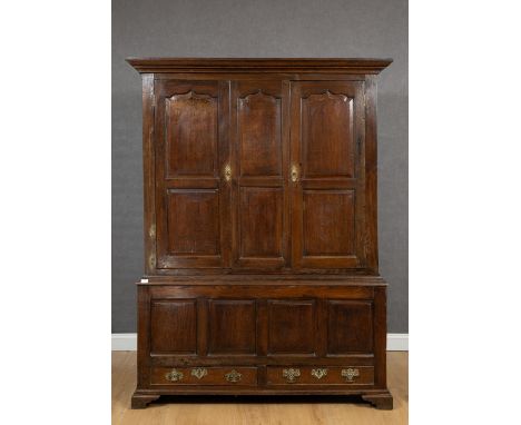 An 18th century oak cupboard with two panelled doors above a chest with two short drawers, raised on ogee bracket feet, 141cm