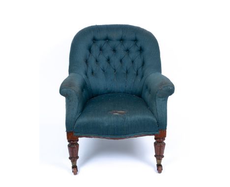 A Victorian mahogany blue button upholstered armchair with scrolling arms and carved turned tapering legs terminating in cera