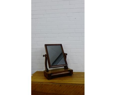 A 19th century mahogany dressing mirror with a rectangular plate on shaped side supports with a cushion fronted drawer to the