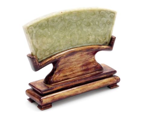 A Chinese carved jade plaque, carved ub klow relief with archaic designs, on a hardwood stand, 11.5cm high overall. 