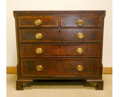 A Georgian oak and mahogany cross banded chest of three long and two short drawers with brass handles standing on bracket fee