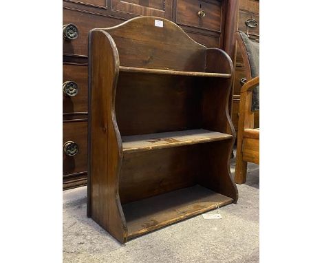 A small stained pine three tier open waterfall bookcase, dating from the first half of the 20thc., raised on panel end suppor