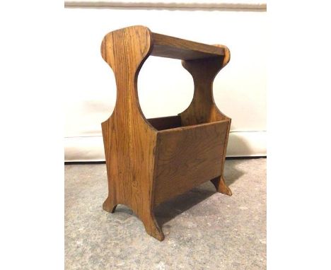 A mid to late 20thc. oak magazine stand, the tray top above two division magazine well to base, raised on shaped panel end su