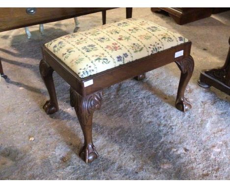 An early 20thc Chippendale style footstool, the drop in floral upholstered seat pad above acanthus and scroll carved cabriole