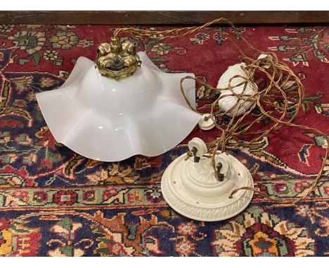 A rise and fall ceiling light fitting with a floral ceramic ceiling rose above a floral brass light fitting and an opaline gl