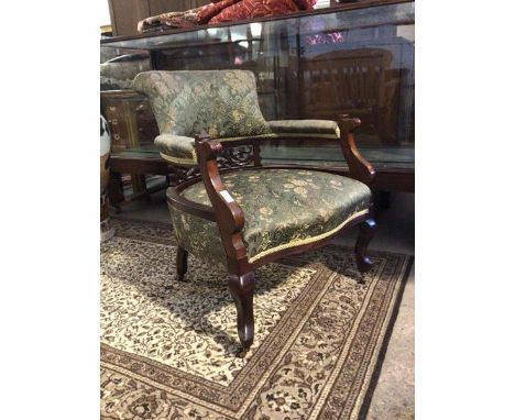 A late Victorian mahogany framed tub shaped open armchair, the back, arms and seat upholstered in a green floral damask fabri