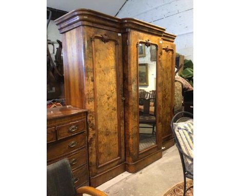 A Victorian figured and burr walnut breakfront triple wardrobe, the central mirrored cupboard door enclosing open shelf, thre