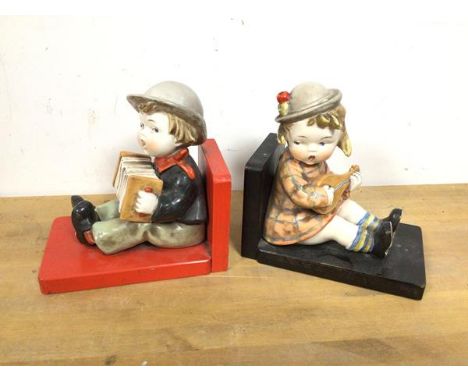 A pair of vintage bookends, each with a seated painted ceramic child playing an instrument (each: 16cm x 16cm x 10cm)