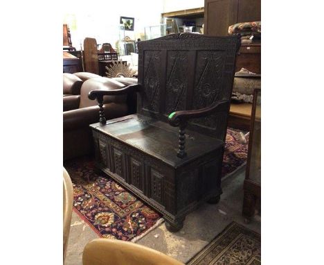 A Victorian carved oak hall settle of an earlier design, the three panel back with lozenge carvings above a box seat with hin