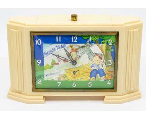 A novelty Art Deco ivory coloured bakelite alarm clock, designed to face with a Japy cartoon of a young girl and a donkey, di