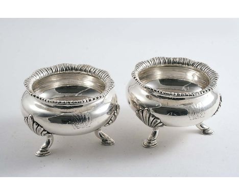 A PAIR OF VICTORIAN SQUAT CIRCULAR SALTS on three fluted legs with stepped hoof feet and shaped, gadrooned rims, crested, by 