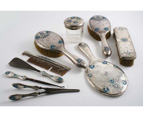 AN EDWARDIAN ART NOUVEAU DRESSING TABLE SET decorated with blue & green enamel and stamped florets to include a hand mirror, 