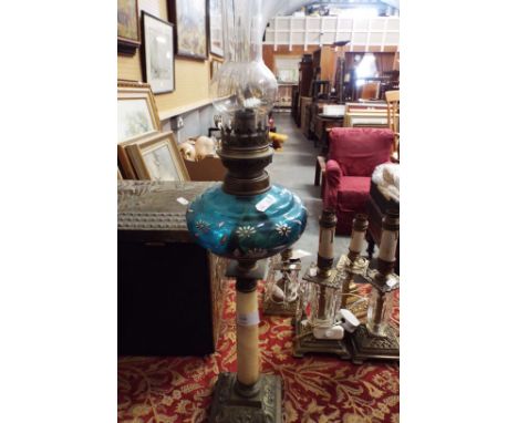 An ornate brass and glass oil lamp having blue glass bowl and soapstone pillar