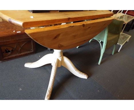 A drop leaf circular pine table on tripod base