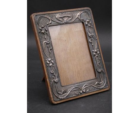 An early 20th century English hallmarked silver cedar backed easel picture frame with embossed Art Nouveau floral design. Hal