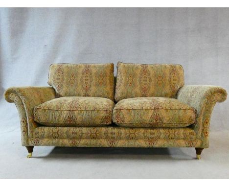 A large Parker Knoll two seater Burghley sofa in Baslow Medalli gold upholstery raised on turned tapering supports on brass c