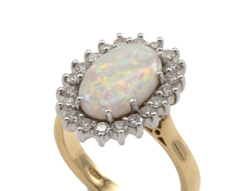 18ct gold, diamond and opal cluster ring, the central oval cabochon stone measuring 8mm x 8mm, surrounded by a border of bril