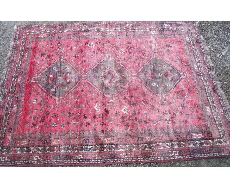 20th C Afgan red ground wool carpet with three central medallions and geometric border size approx. 210cm x 285cm