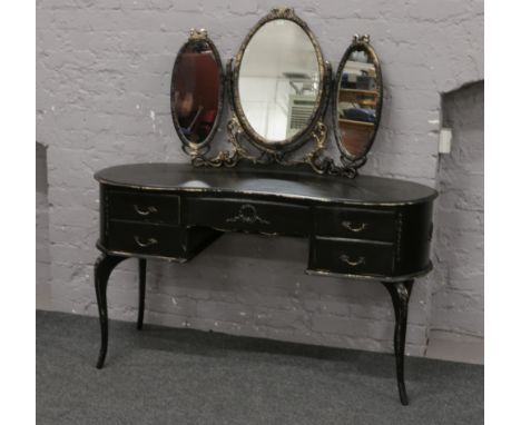 A painted black dressing table of kidney shape with gilt decoration raised on cabriole supports.