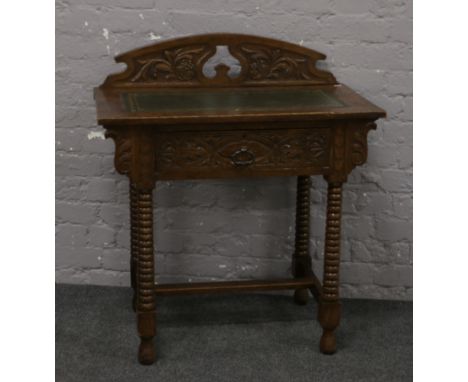 A carved oak leather inset writing table raised on bobbin turned legs.