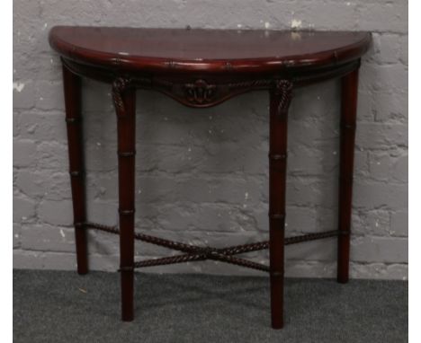 A demi lune side table with carved ropework decoration.