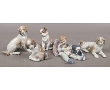 Five Lladro and Nao porcelain figures, four formed as puppies, the other as a young boy asleep with puppies and dog.