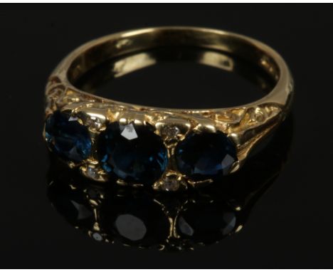 An 18ct gold Victorian style three stone sapphire ring in carved half hoop setting with diamond points, sapphires approximate