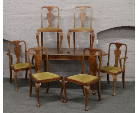 A bur walnut extending dining table with extra leaf raised on carved cabriole legs along with a set of six chairs.