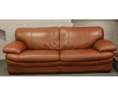 A tan coloured good quality three seat settee raised on bracket feet.