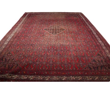 Large 20th century Caucasian wool floor rug with a large central panel decorated with geometric detail on a principally red b