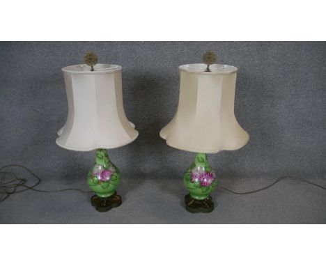 A pair of hand decorated ceramic baluster shaped table lamps with gilt metal filigree finials resting on dolphin supports. H.