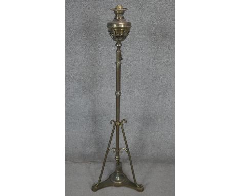 A Victorian brass floor standing oil lamp with tripod base and stylised foliate design. H.140cm 