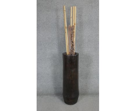 A large palm trunk umbrella stand with bamboo canes and carved Balinese panel. H.95 D.29CM 